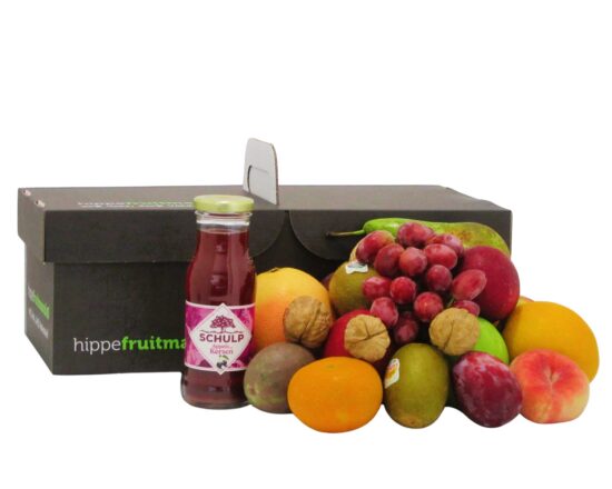 compacte fruitmand van Hippefruitmand.nl met vers, kleurrijk fruit en een glazen flesje Schulp appel-kersensap