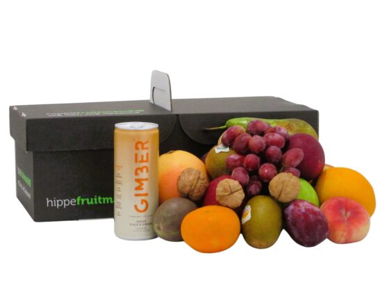 fruitmand gevuld met vers seizoensfruit zoals appels, druiven en sinaasappels, met een blikje GIMBER Perzik gemberdrank