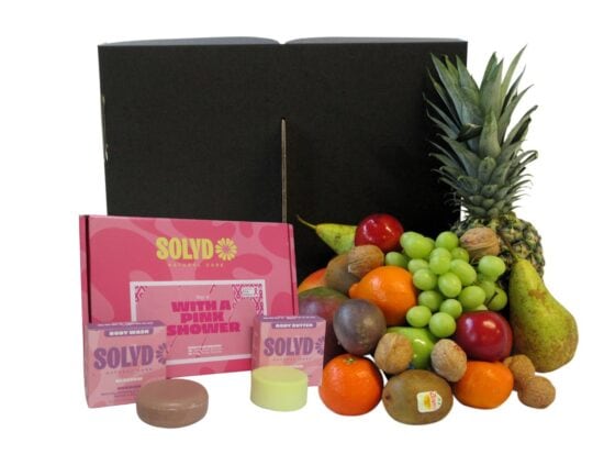 Duurzame fruitbox van Hippefruitmand gevuld met mango, ananas, druiven en appels, samen met de Pink Shower giftbox van SOLYD voor Pink Ribbon